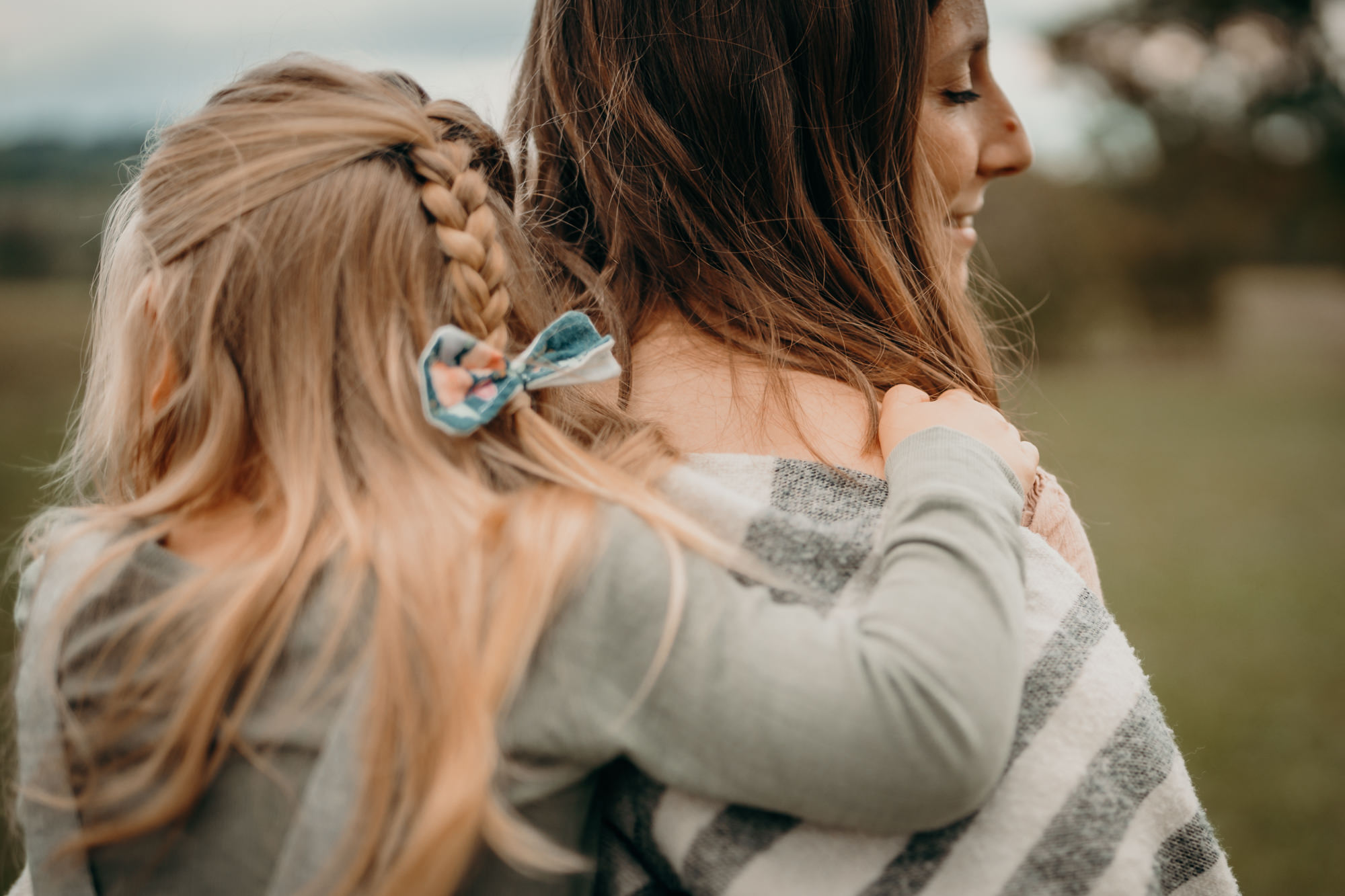 Das Foto zeigt eine Mama, die ihr Kind Huckepack trägt. Das Bild zeigt die tiefe Verbindung der beiden.