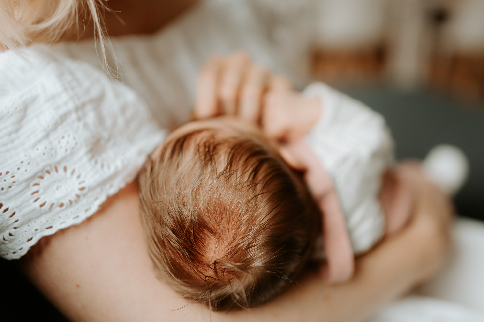 Das Bild zeigt ein Neugeborenes im Arm seiner Mama